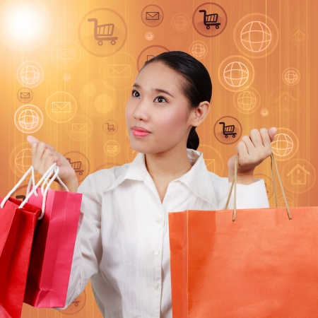 Shopping women show empty hands and hold shopping bags.On background with symbols network and Internet. Concept Communication and borderless business spending.の写真素材