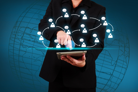 Businessman holding a tablet with globe and community iconsの写真素材