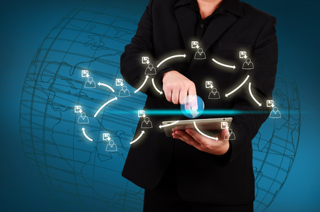 Businessman holding a tablet with globe and community iconsの写真素材