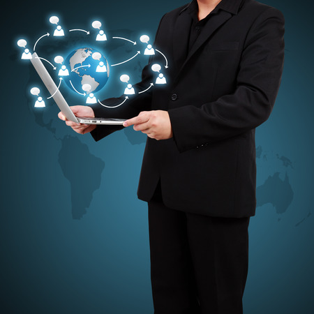 Businessman holding a laptop with social network icons coming outの写真素材