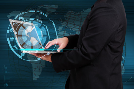 Businessman holding a laptop with globe and icon application on virtual screenの写真素材