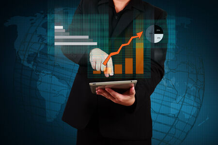businessman holding a tablet showing business graph on virtual screenの写真素材