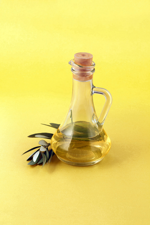 glass bottle of pure fresh olive oil and leaf - clipping path - bottle behind olive branchの写真素材