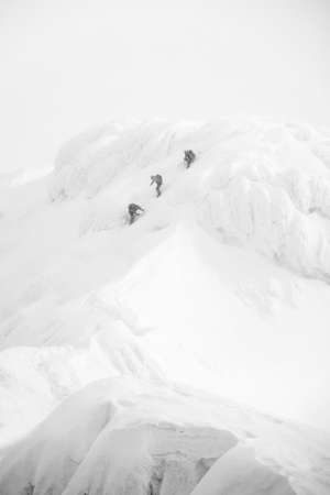 Climbers walking on the top of a mountain covered with snowの写真素材