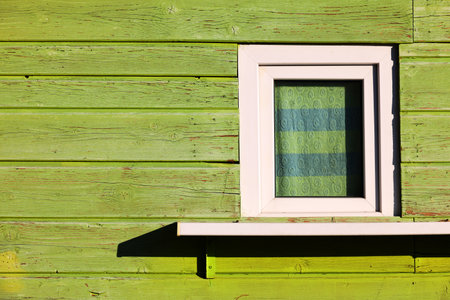 Window on the wall of an old house with green wooden planksの写真素材
