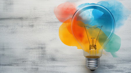 Illuminated Bulb Amidst Colorful Artistic Watercolor Splashes on Textured Backgroundの素材
