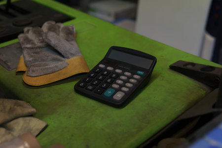 A pair of work gloves and a calculator, on a forklift