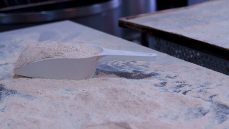 White scoop filled with flour on a baking workstationの写真素材
