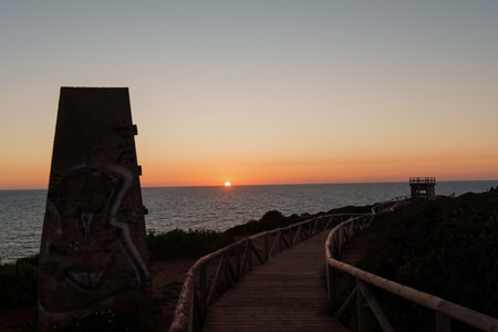 Wood catwalk leading to the ocean at sunset with pillar with graffitiの写真素材