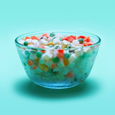 Glass bowl with frozen vegetables on a green backgroundの写真素材