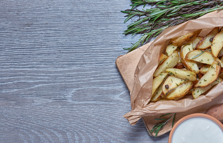 Baked potatoes with rosemary on a gray background with wood textureの写真素材