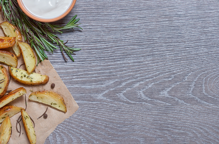 Baked potatoes with rosemary on a gray background with wood textureの写真素材
