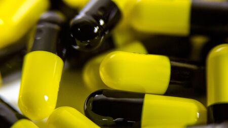 Close up of many black and yellow pills and tablets medicine isolated on white background. Prescription drugs. Medication, painkillers and drug abuse concept.の写真素材
