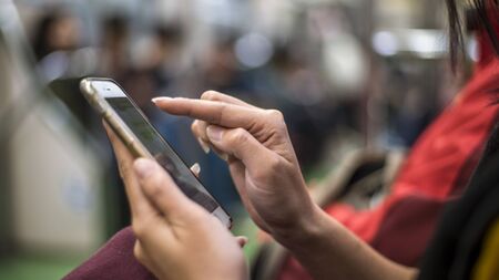 Asian tourist woman sit down in metro and holds smartphone. Passenger using technology phone in...
