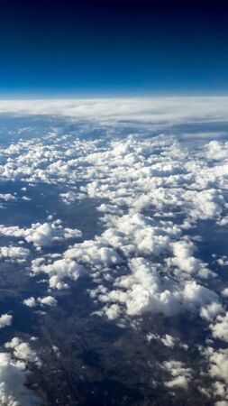 The beautiful cloudscape with clear blue sky. Panorama above white clouds as seen through window of...