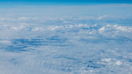 The beautiful cloudscape with clear blue sky. Panorama above white clouds as seen through window of...