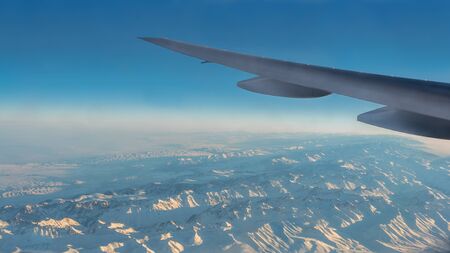 Traveling by air. Wonderful view of the Tian Shan snow mountains and clouds with blue sky from above...