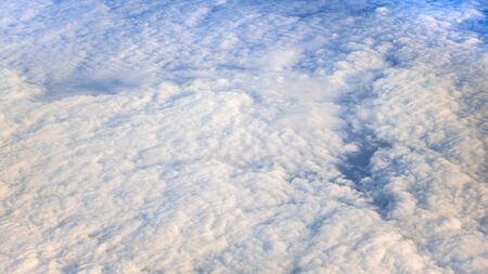 The beautiful cloudscape with clear blue sky. Panorama above white clouds as seen through window of...