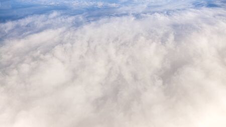 The beautiful cloudscape with clear blue sky. Panorama above white clouds as seen through window of...