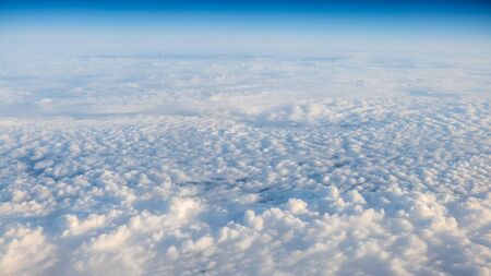 The beautiful cloudscape with clear blue sky. Panorama above white clouds as seen through window of...