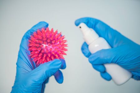 Scientific with blue gloves use sanitizer for Coronavirus red model. Preventive measures against Covid-19. Ðntibacterial gel alcohol-based hand-washing spray. Epidemic virus outbreakの写真素材