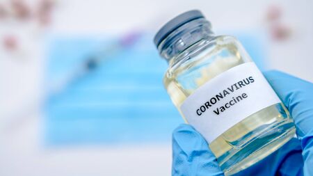 Doctor wearing gloves and holding vaccine for Covid-19. Coronavirus has caused emergency situation. Concept of pandemic quarantineの写真素材