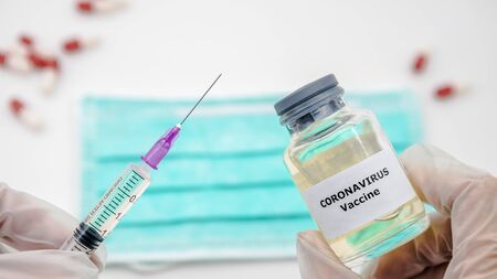 Scientist with vaccine and syringe injection for Covid-19 in the scientific chemical laboratory. Flu coronavirus pathogen that attacks the respiratory tract. Pandemic virus infection conceptの写真素材