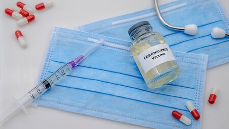 Vaccine and syringe injection for Covid-19 on face mask in the scientific chemical laboratory. Flu...