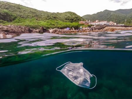 Medical face mask floating underwater. Used surgical mask on ocean water