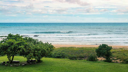 Ocean wave rolling towards sandy beach with green trees of Taiwan island. Sea view of nature...
