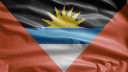 Antigua and Barbudan flag waving in the wind. Close up of Antigua and Barbuda banner blowing, soft and smooth silk. Cloth fabric texture ensign background.の写真素材