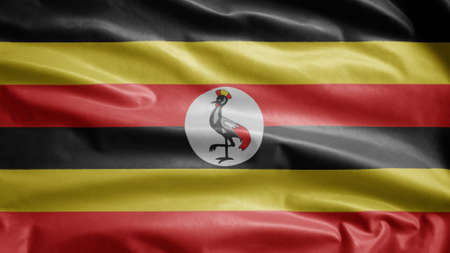 Ugandan flag waving in the wind. Close up of Uganda banner blowing, soft and smooth silk. Cloth fabric texture ensign background. Use it for national day and country occasions concept.の写真素材