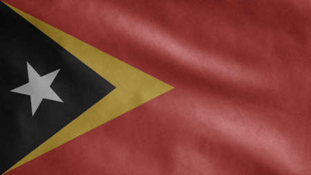 Timorese flag waving in the wind. Close up of East Timor banner blowing, soft and smooth silk. Cloth fabric texture ensign background. Use it for national day and country occasions concept.の写真素材