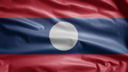 Laotian flag waving in the wind. Close up of Laos banner blowing, soft and smooth silk. Cloth fabric texture ensign background. Use it for national day and country occasions concept.の写真素材