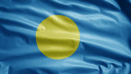 Palauan flag waving in the wind. Close up of Palau banner blowing, soft and smooth silk. Cloth fabric texture ensign backgroundの写真素材