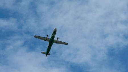 A commercial passenger propeller aircraft across flying over head. Jet airplane flying low with blue...