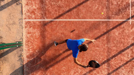 View from above of a professional paddle tennis player who is going to hit the ball with the racket on an outdoor court.の写真素材