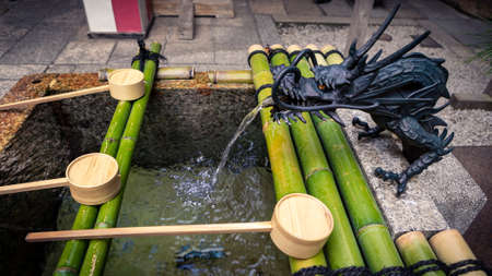 Purification by washing hand at the fountain of sanctuary in Kyoto. Water running from mouth of a dragon at Japan. Entrance of a Japanese shinto temple.の写真素材