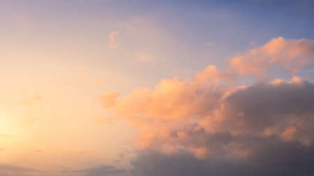 Wonderful view of cumulus clouds sky with the orange sun light at sunset of summer. Beautiful cloudscape as nature background panorama at sundown. Weather of natural daylight golden sunshineの写真素材