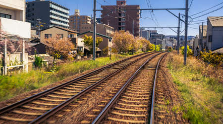 Japanese Kyoto local train traveling on rail tracks along the railway at spring season. Scene of railroad and train travels landscape. Transport for sightseeing Japan conceptのeditorial素材