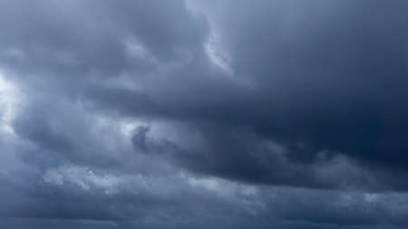 Dark storm clouds make the sky in black. The rain is coming soon. Beautiful heaven with dramatic light, sometimes heavy clouds mass charged. Abstract nature background.の写真素材