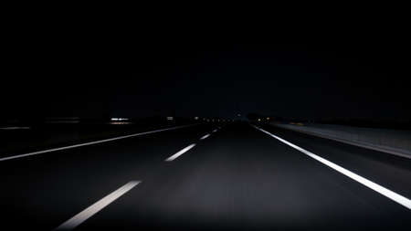 POV view of car driving on road of highway at night in Spain. Drive on an empty road in the dark evening. A car drives on a freeway. Asphalt with white line at new road.の写真素材