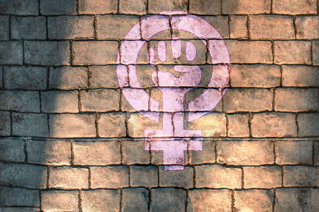 A drawing of strong fist raised up with woman gender with copy space aside for promotional text or advertisement on stone brick wall with natural sunlight. Feminism symbol girl power concept.の写真素材