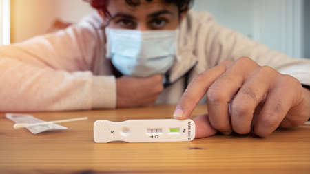 Unhappy caucasian man holding a positive buffer dropper for seft detection at home. PCR test after...