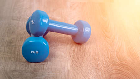 Exercise with two blue dumbbells, preparing for sports training at house indoor. Fitness workout exercises at home.の写真素材