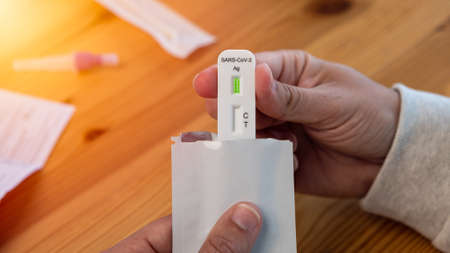 Hands of man unpacking test kit at home. The rapid test can be done in your home with results for in...