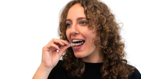 Adult woman holding invisible orthodontic braces. Female hand applying dental aligner retainer of...