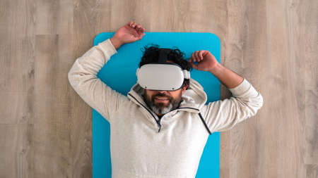 Top view portrait of tired caucasian fitness man resting after make exercise with a vr headset....