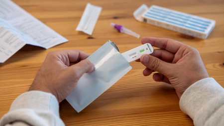Hands of man unpacking coronavirus test kit at home. The rapid test can be done in your home with...
