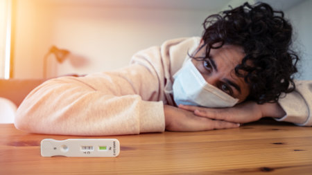 A sad caucasian man makes a rapid home test device for Covid19 virus with a positive result and...